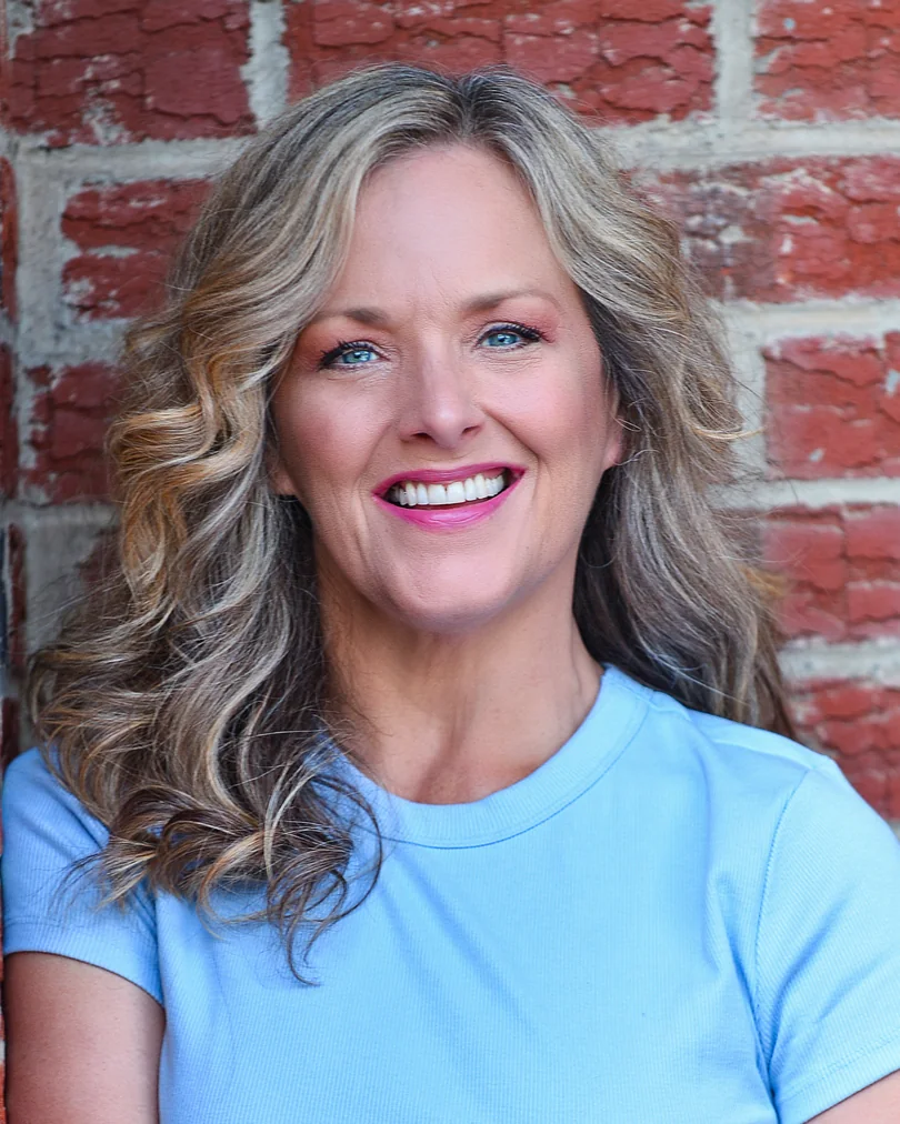 Outdoor headshot with silver hair and a light blue top