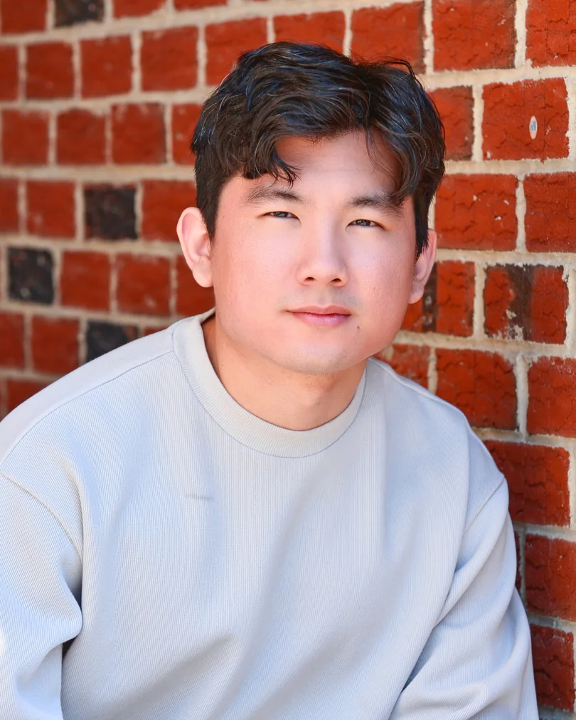 Outdoor actor portrait in a light shirt against brick