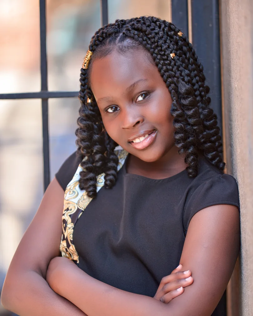 Child actor headshot with braids and a soft outdoor background