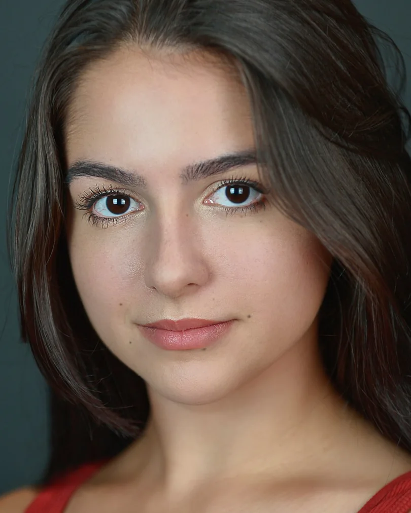 Professional headshot in a red top with a dark studio background
