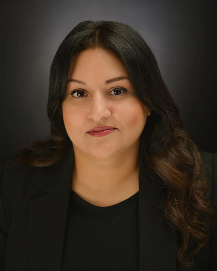 Professional portrait in a black blazer with a dark studio background