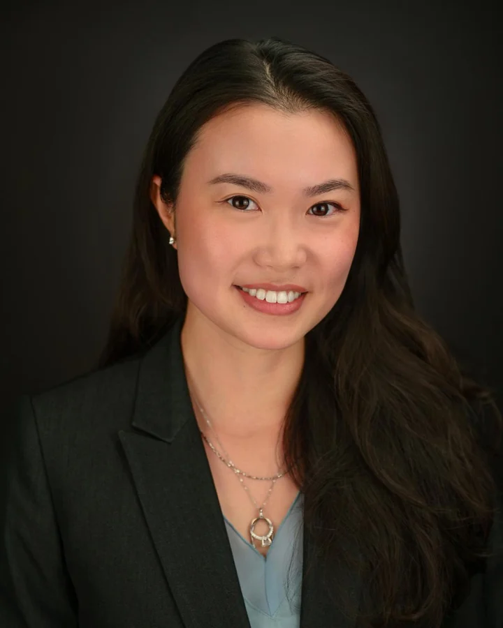 Professional headshot in a black blazer with a soft studio background
